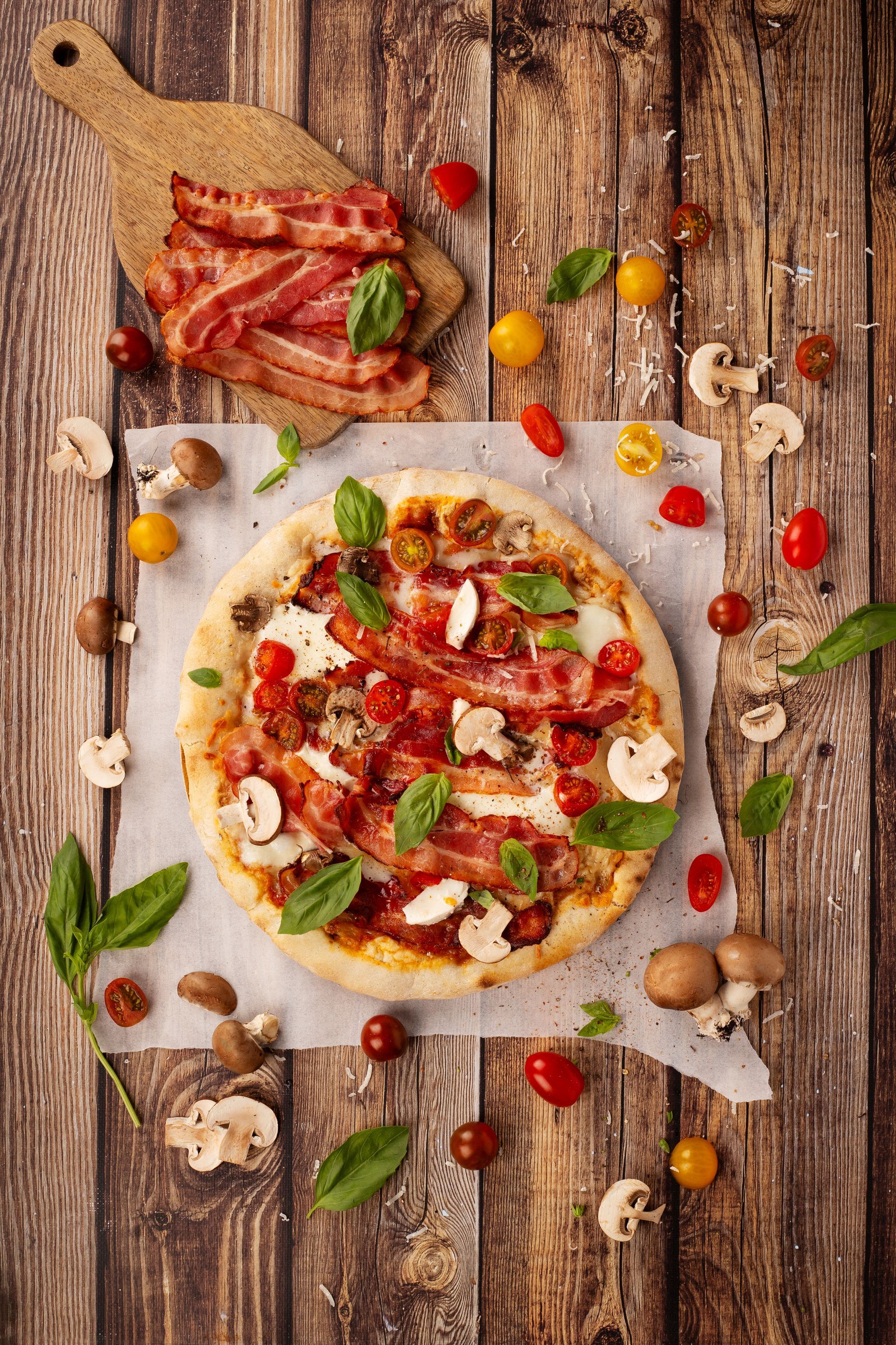 Pizza completa con crema, tomates cherry, champiñones, albahaca y lonchas de bacon crujiente.