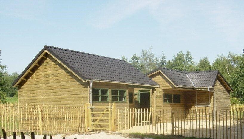 Houten dierenverblijf en kinderboerderij met zwarte dakpannen, gerealiseerd door A&B Betonbouw.