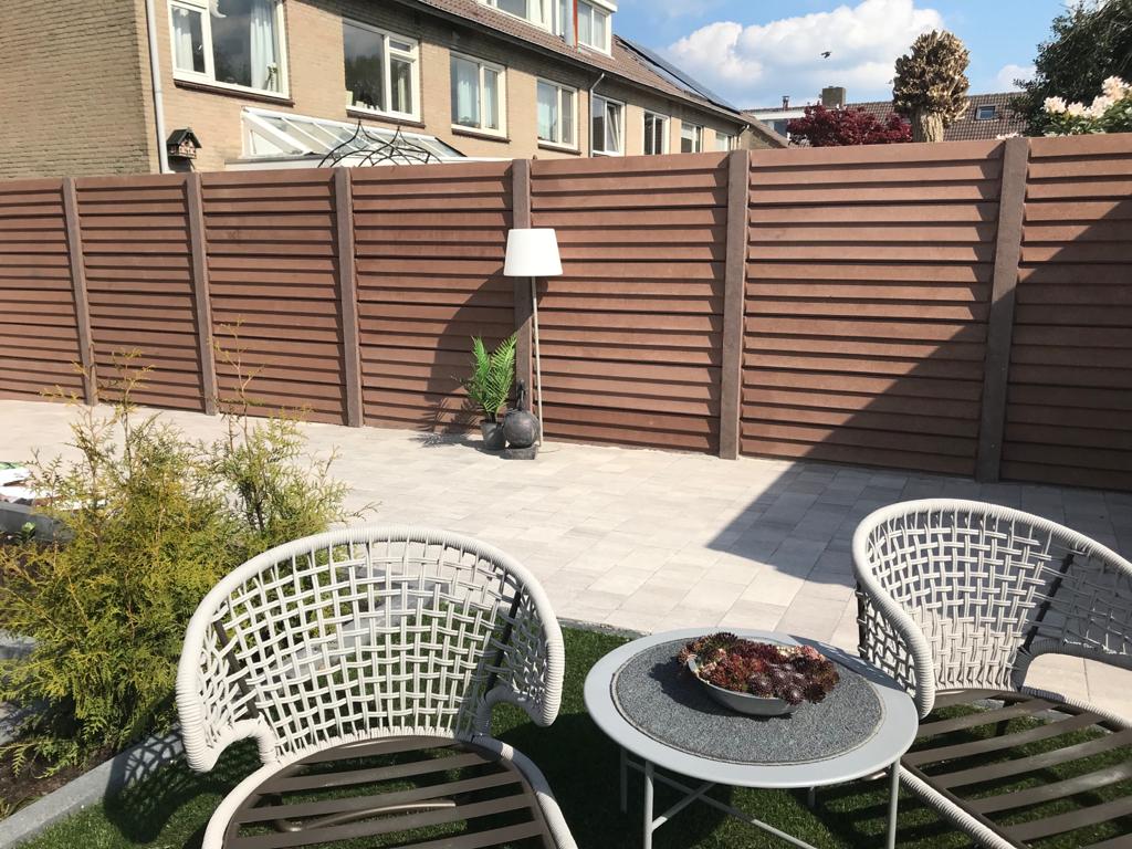 Betonschutting met rabatmotief panelen en houten afwerking, geplaatst door A&B Betonbouw.