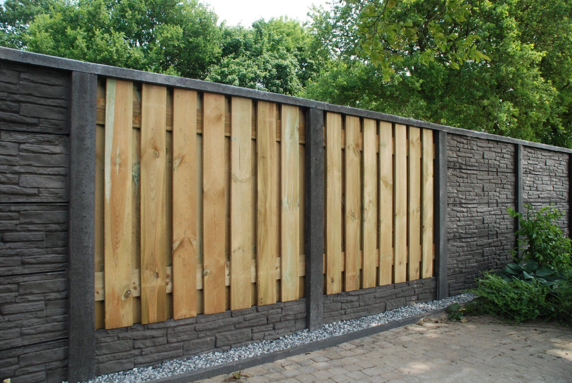 Houten schutting met betonnen onderplaten en handvormsteenmotief, geplaatst door A&B Betonbouw.