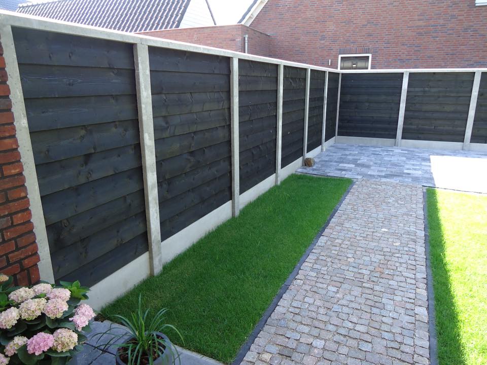 Zwarte betonschutting met potdekseldelen en grijze betonpalen, moderne erfafscheiding van A&B Betonbouw.
