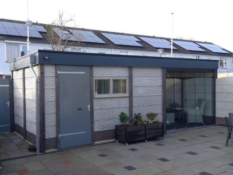 Betonnen berging met plat dak en metalen deur, geplaatst door A&B Betonbouw.