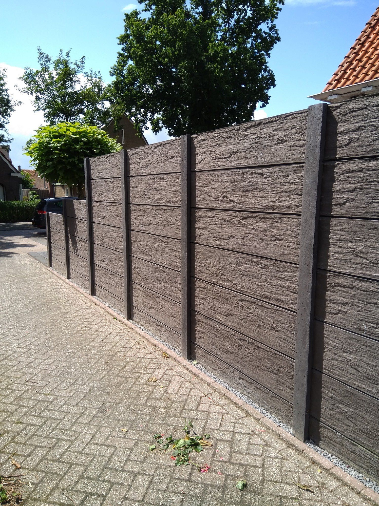 Betonnen schutting met leisteenmotief panelen en antracietkleurige palen, geplaatst door A&B Betonbouw.
