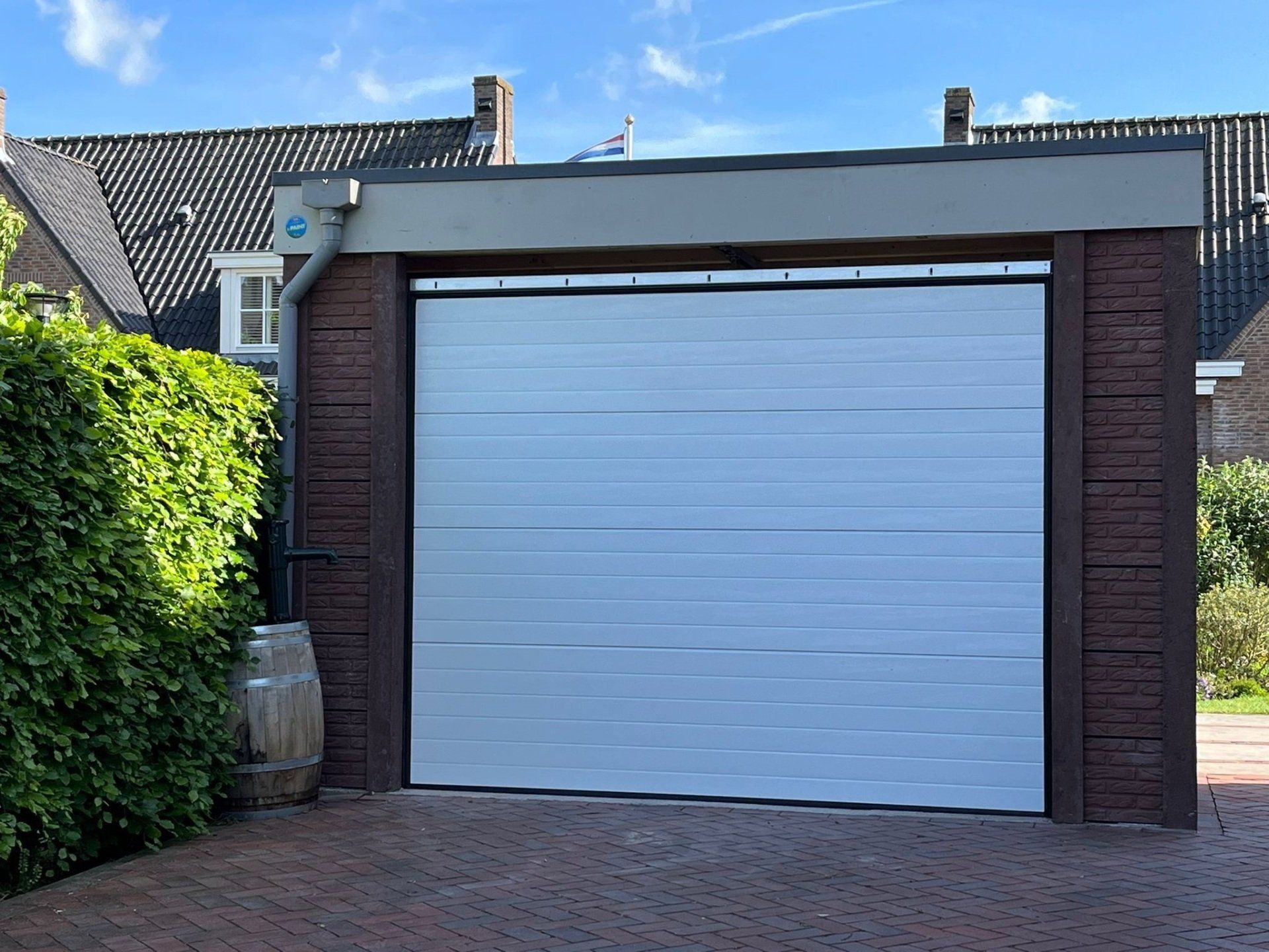Moderne betonnen garage met grijze sectionaaldeur en plat dak, gerealiseerd door A&B Betonbouw.