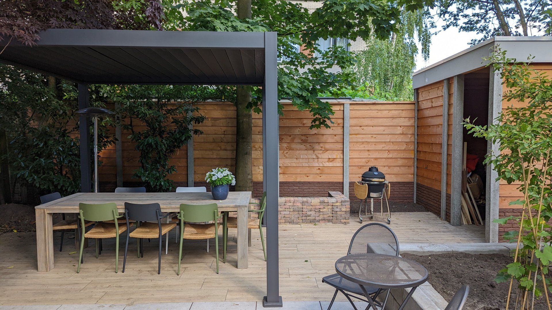 Tuinoverkapping met houten schutting en zithoek, maatwerkproject van A&B Betonbouw.