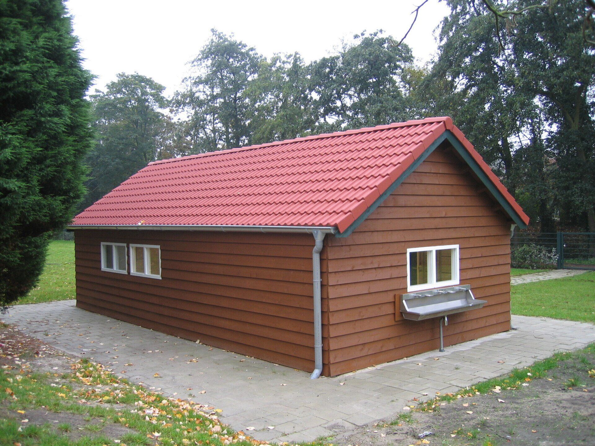 Houten loods met rood zadeldak en witte kozijnen, maatwerkproject van A&B Betonbouw.