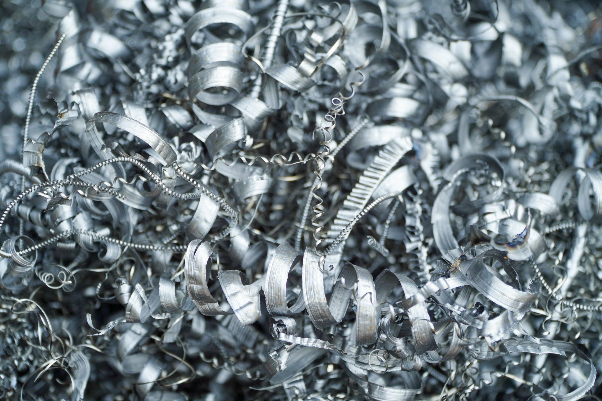 Close-up pile of curled, shiny aluminum metal shavings and turnings