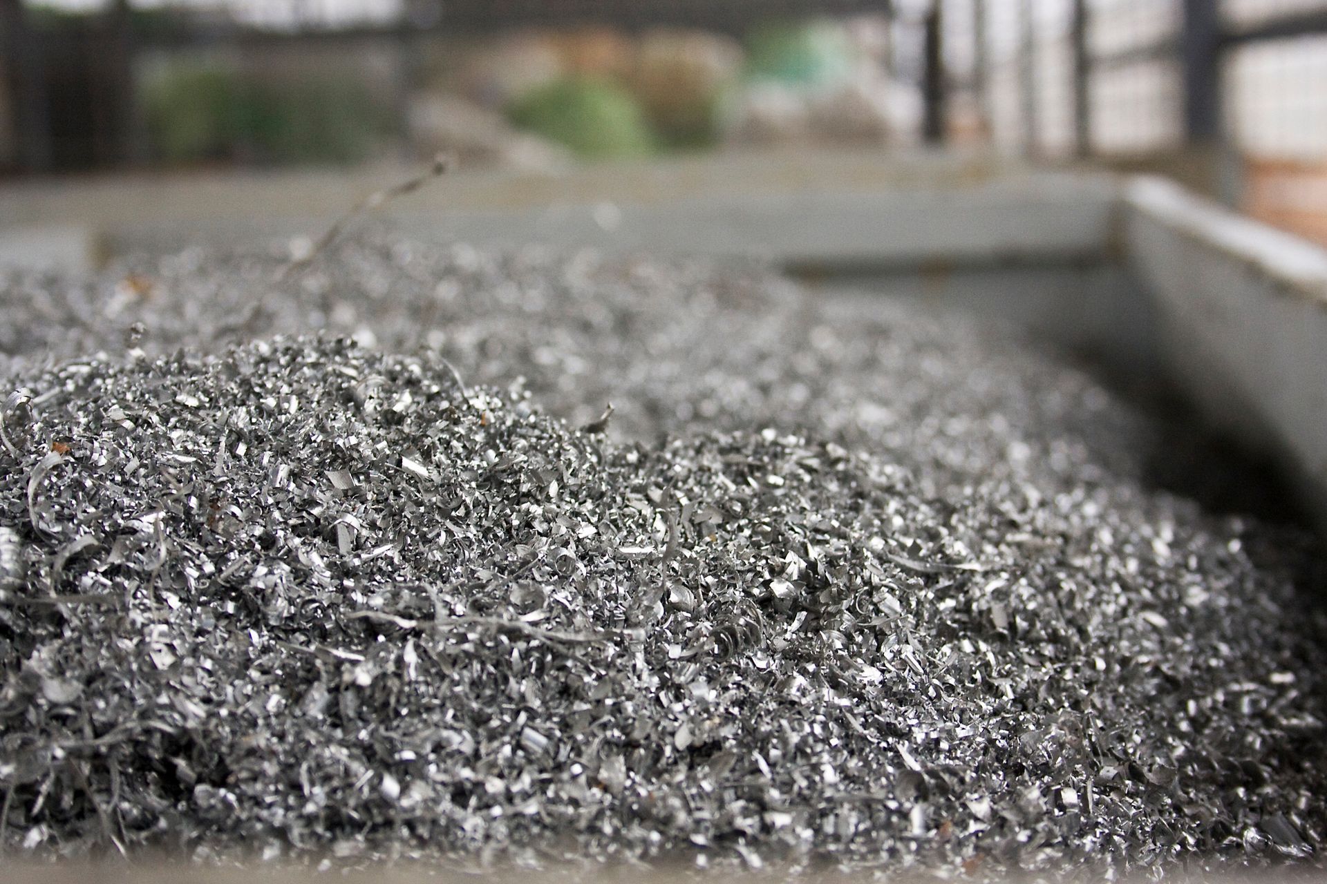 Piles of scrap metal and dust collected for aluminum recycling at an industrial waste facility.