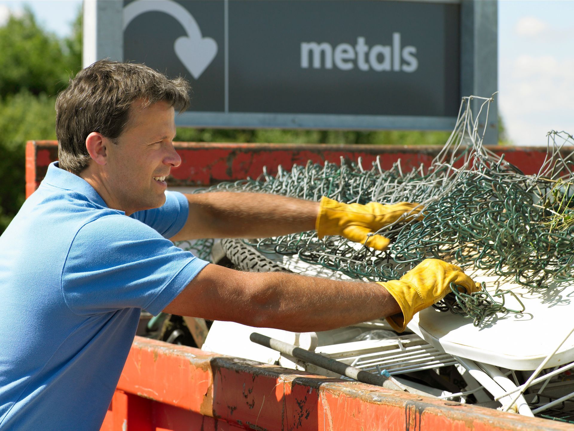 A person in yellow gloves putting a wire on a metal container | Aluminum Scrap Recycling