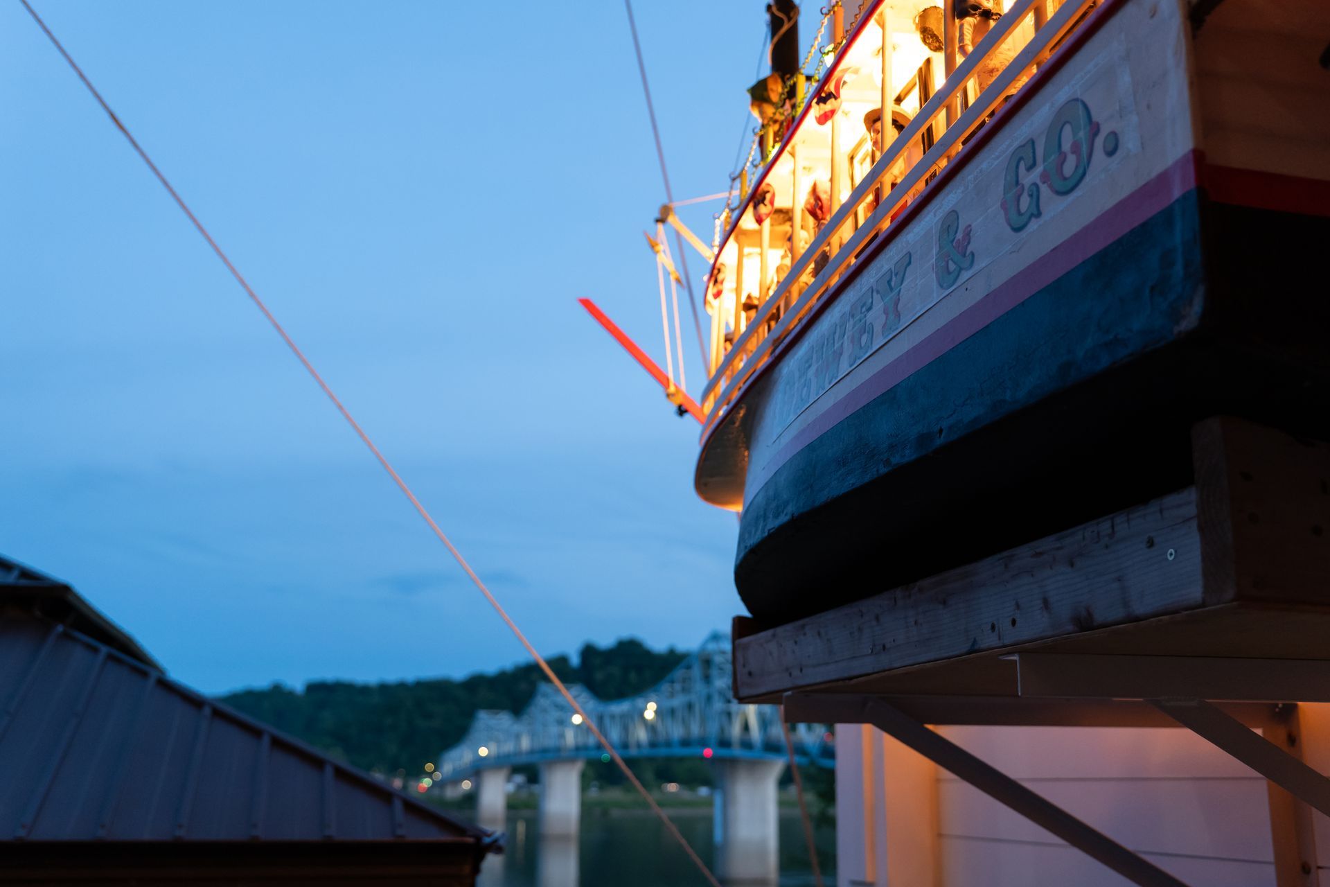 Large bridge at dusk, with blue sky and warm lights reflecting on the water.