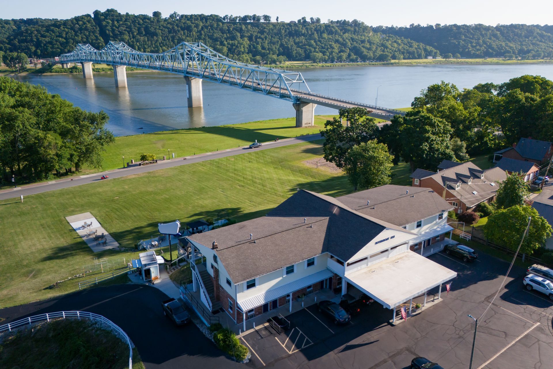 Aerial view of Riverside Inn and parking lot beside a bridge over water and trees