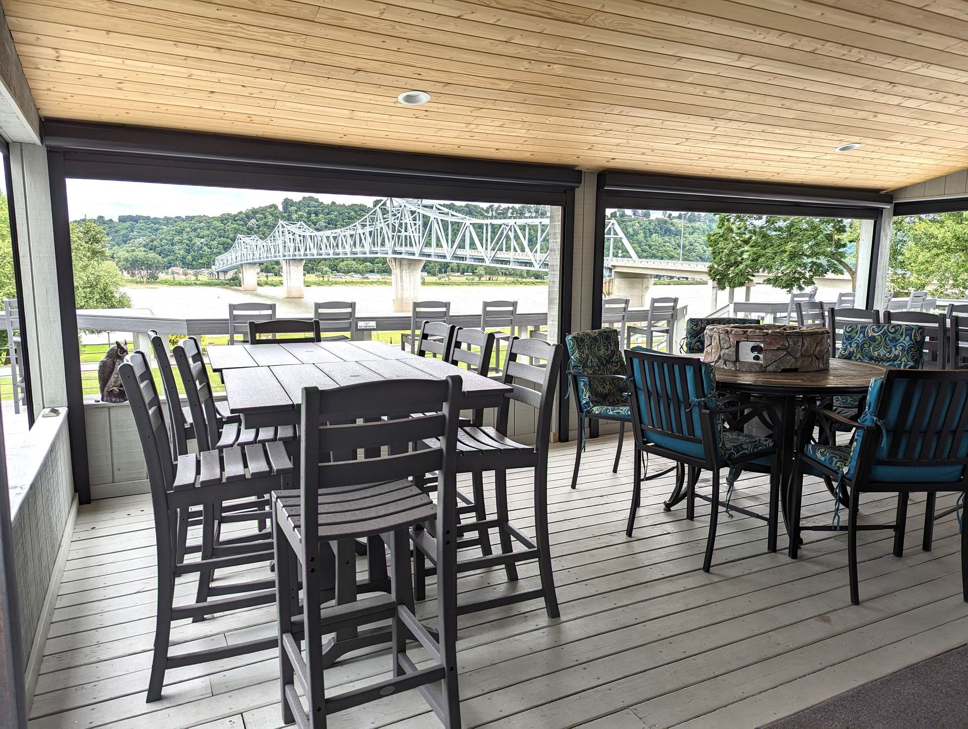 A patio with tables and chairs and a view of a bridge.