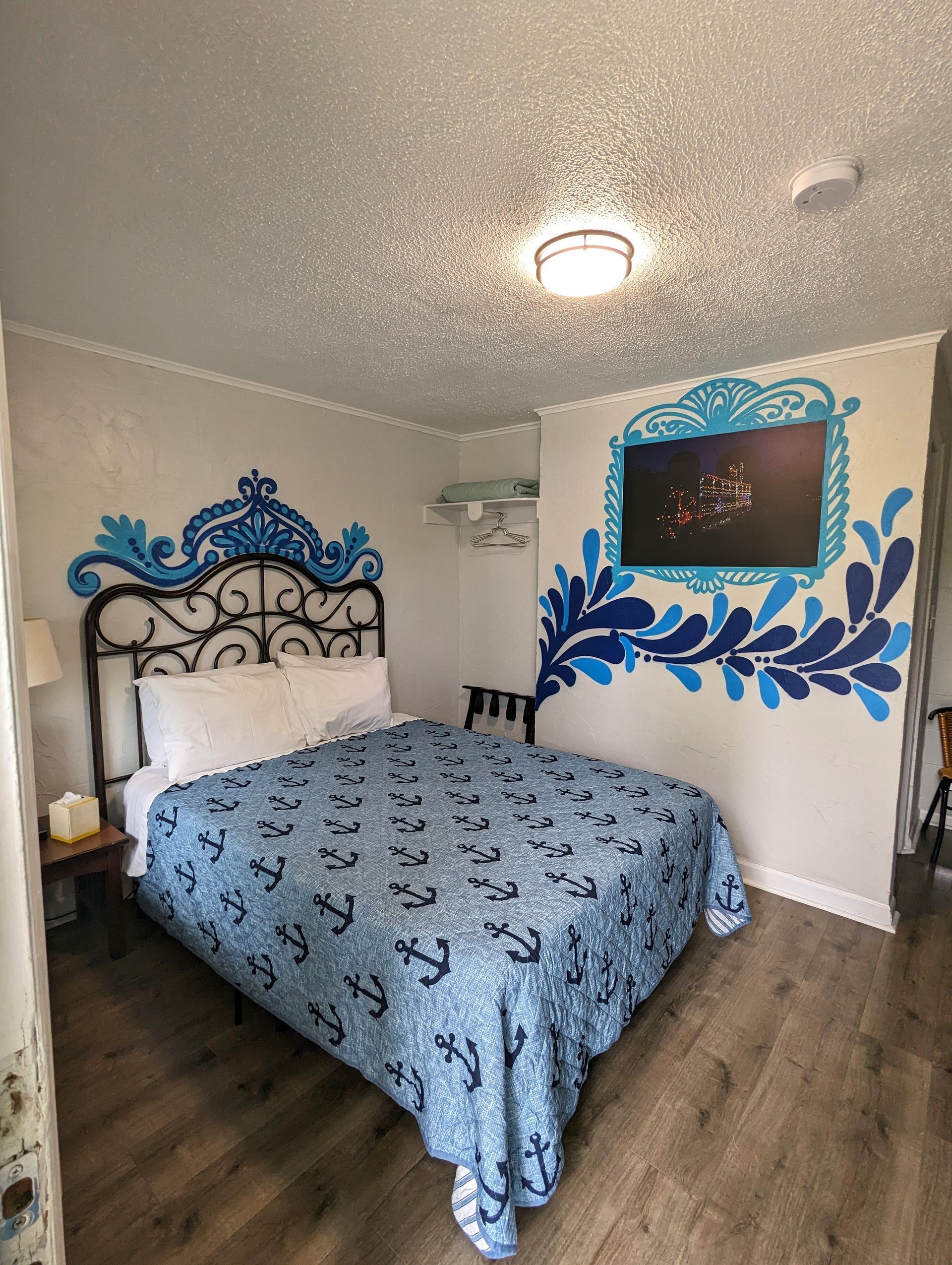 Blue-and-black bedroom with ornate bed, textured ceiling, wall art, and dark wood flooring