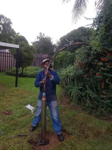 A man is standing in the grass holding a hammer.