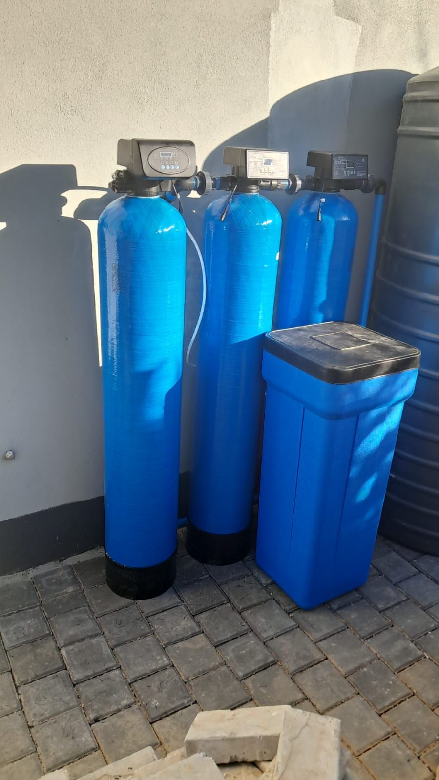 Three blue tanks are sitting next to each other on a brick sidewalk.