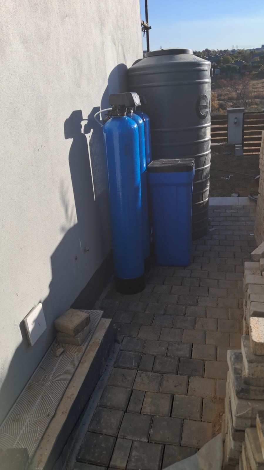 Two blue water tanks are sitting next to each other on a sidewalk.