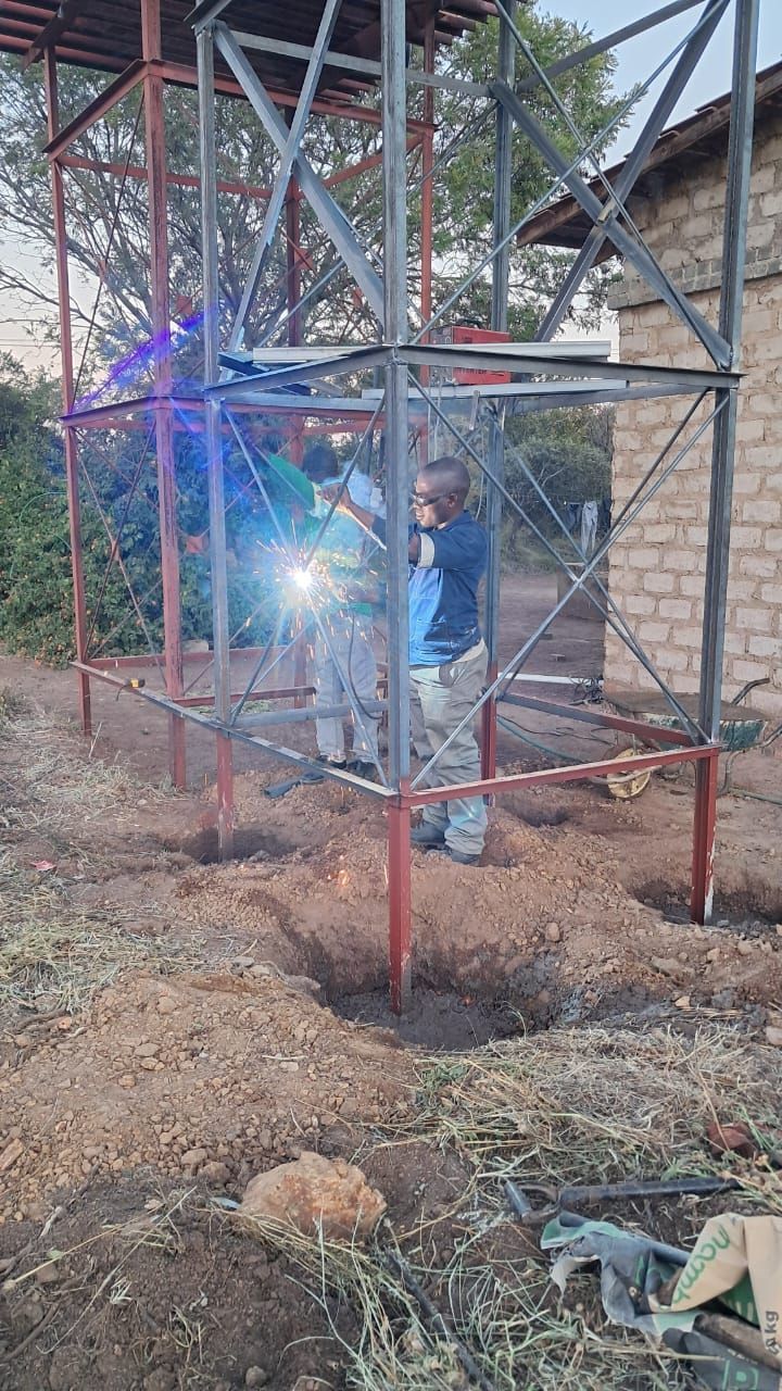 A man is welding a metal structure in a field.