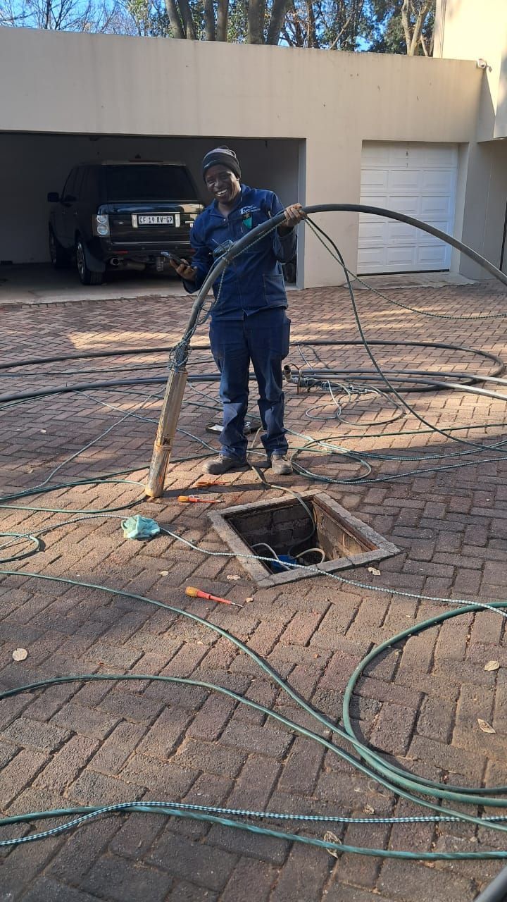 A man is pumping water into a drain in a driveway.