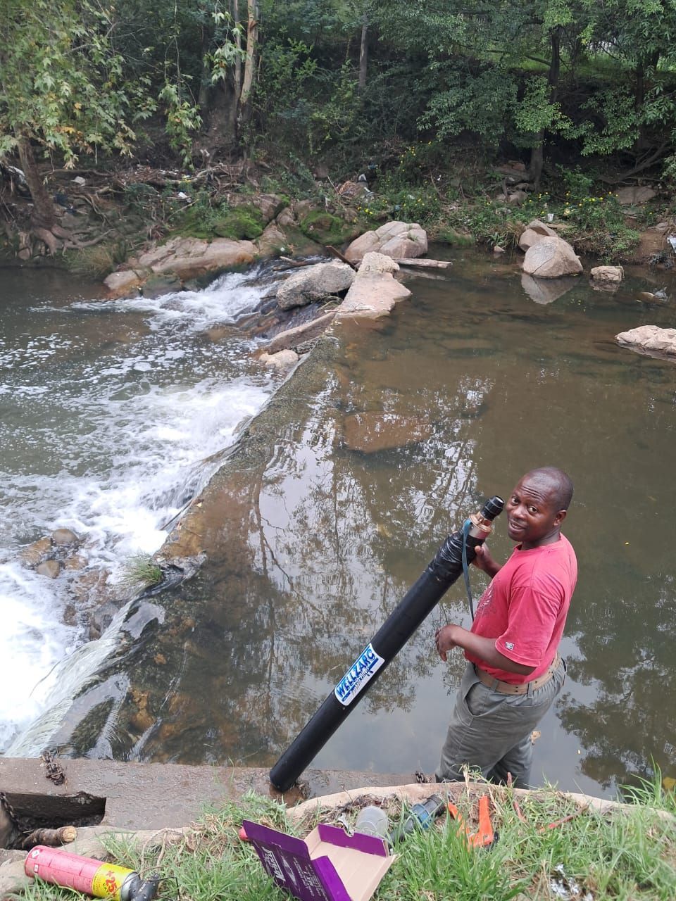A man in a red shirt is standing next to a river