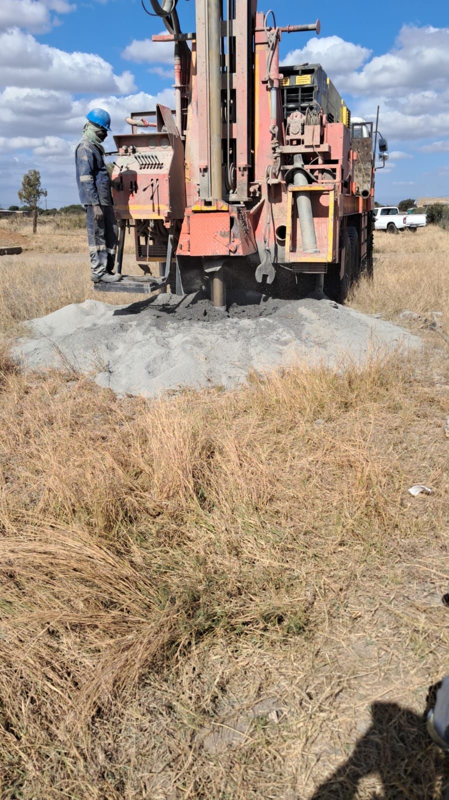 A man is standing next to a machine in a field.
