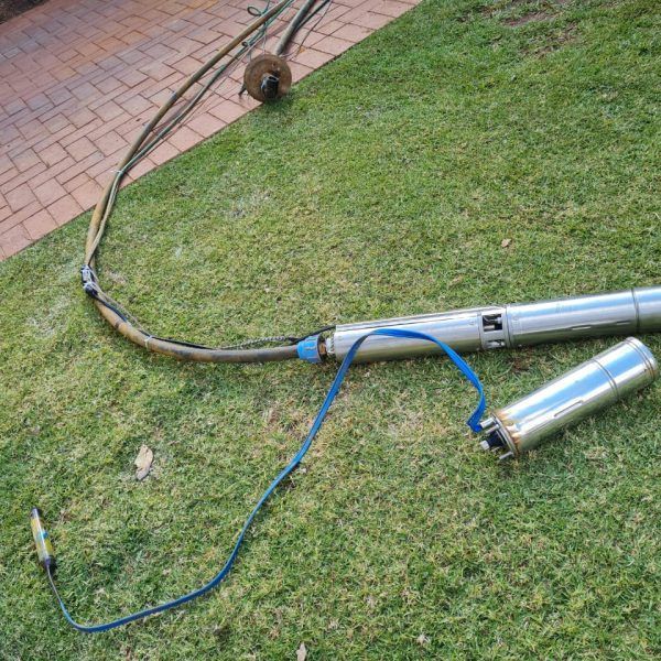 A water pump is sitting on top of a lush green lawn.