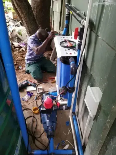 A man is kneeling down working on a water pump.