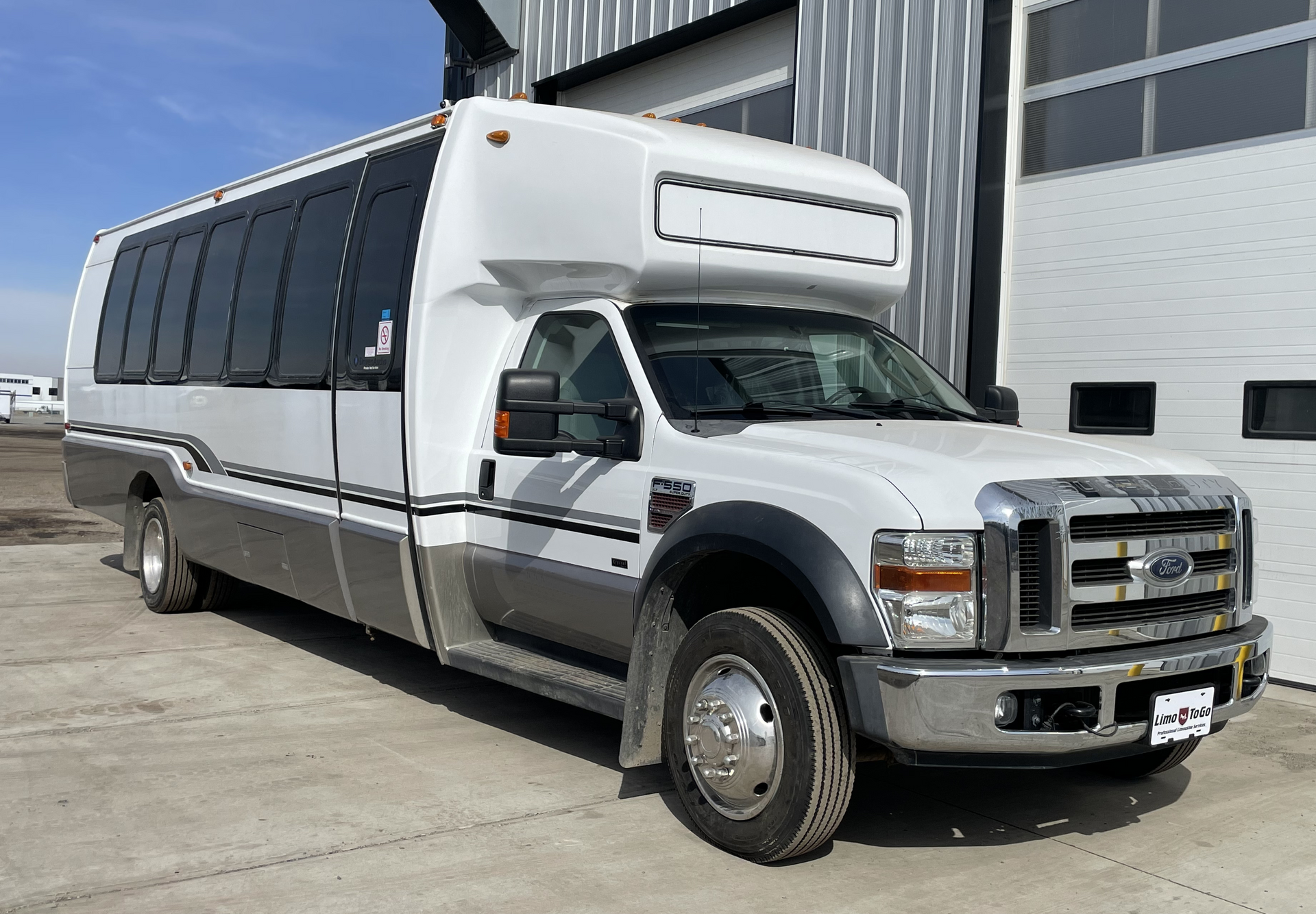 a white bus is parked in front of a garage door .