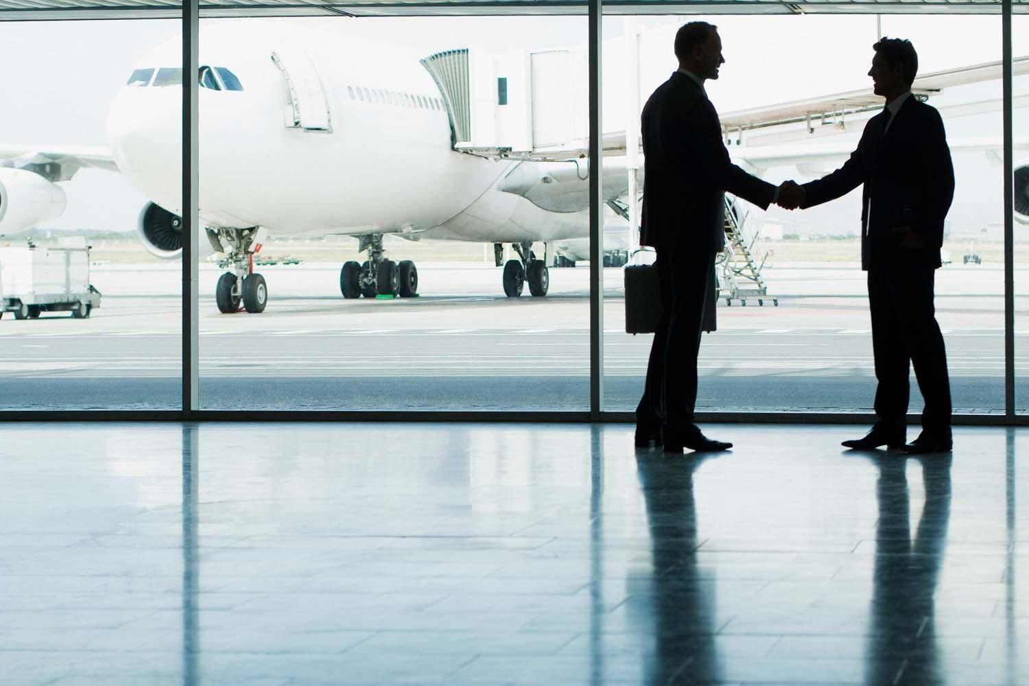 businessmen shaking hands at airport gate