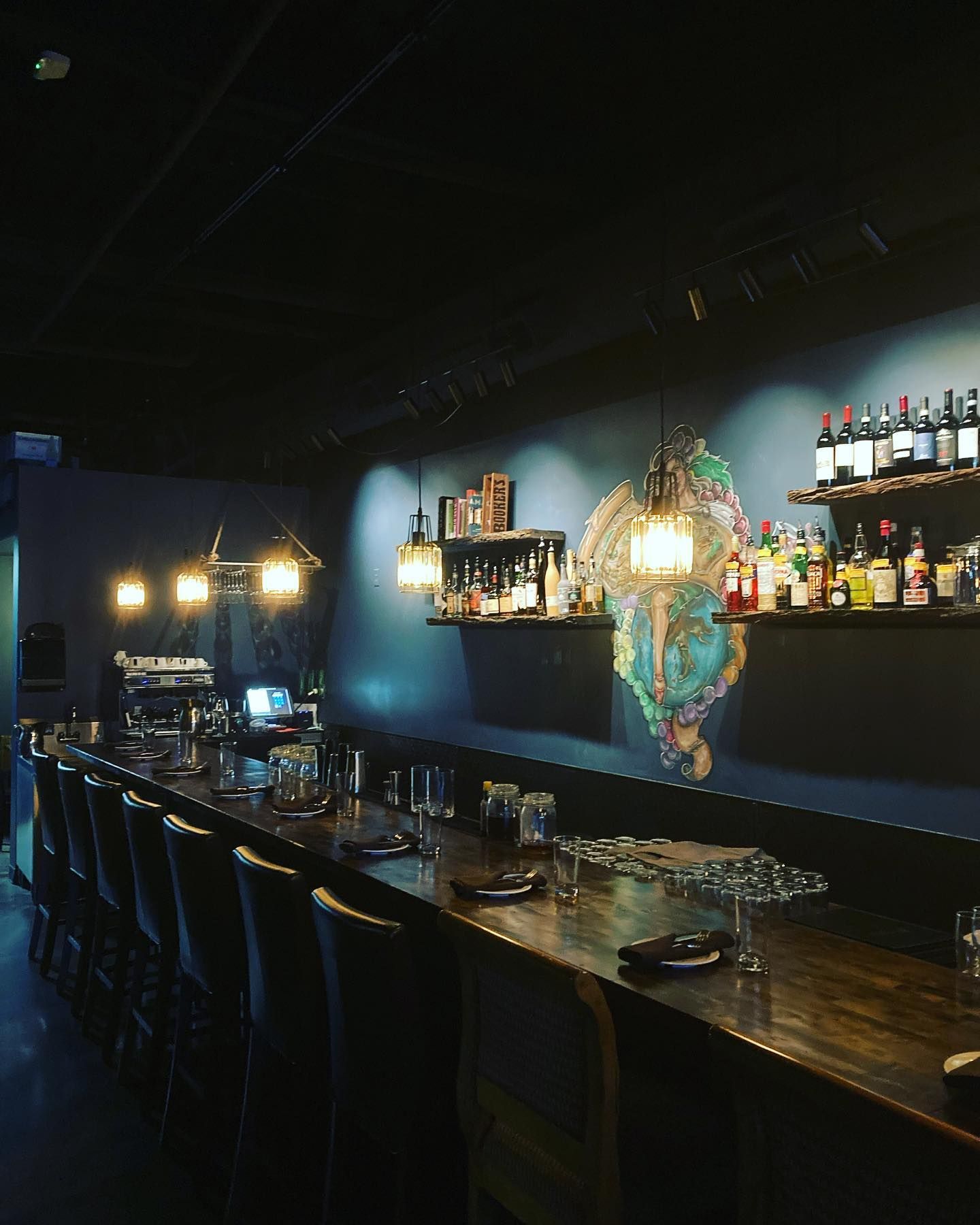 A long bar in a restaurant with bottles on shelves