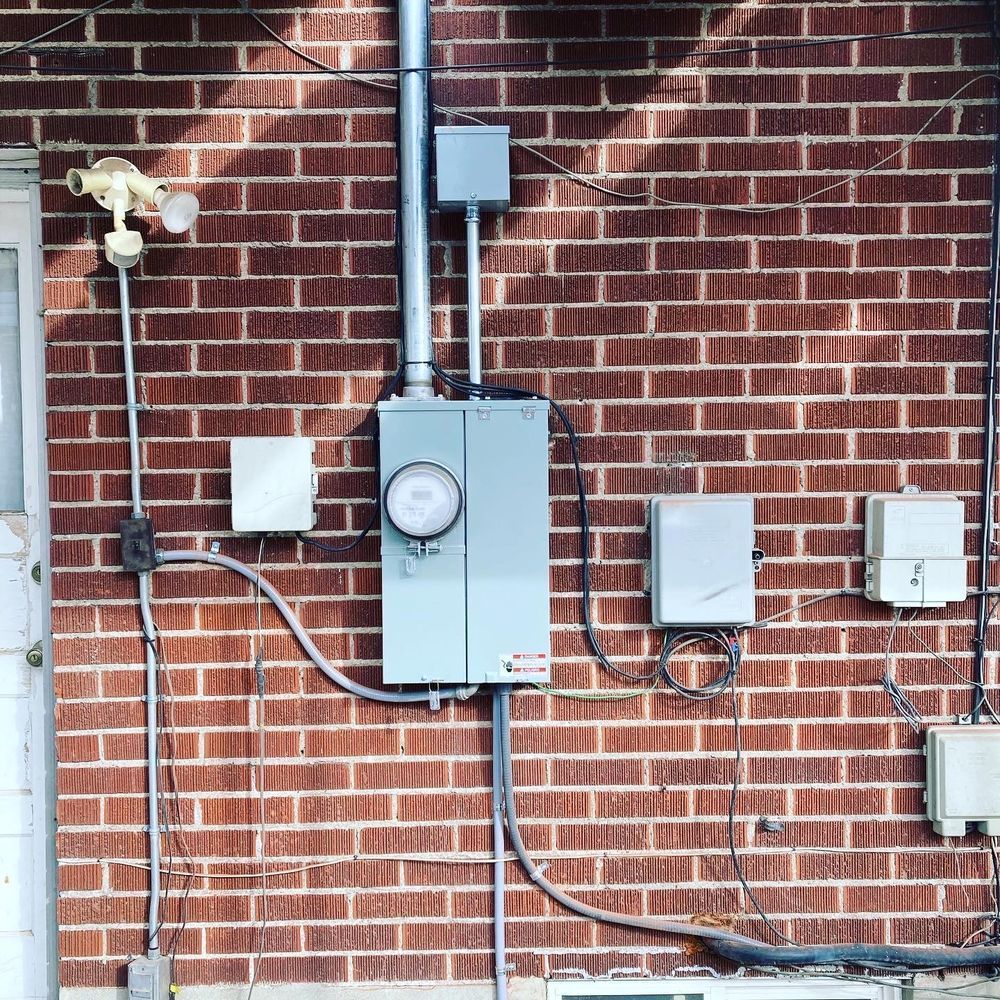 A garbage can is sitting next to a meter on the side of a building.