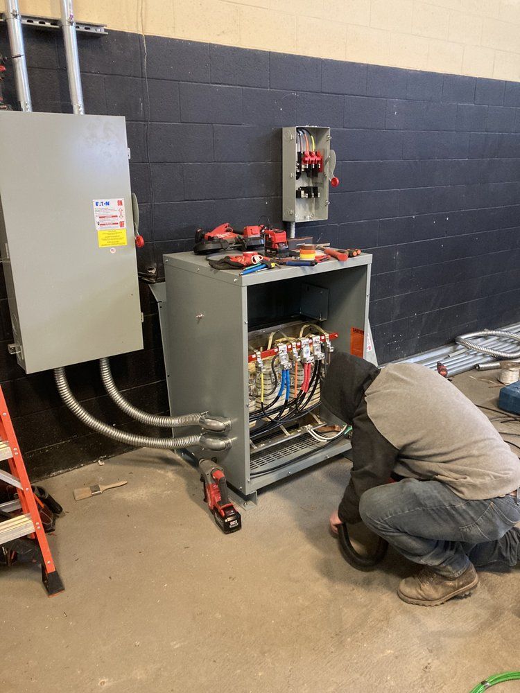 A man is kneeling down in front of a electrical box.