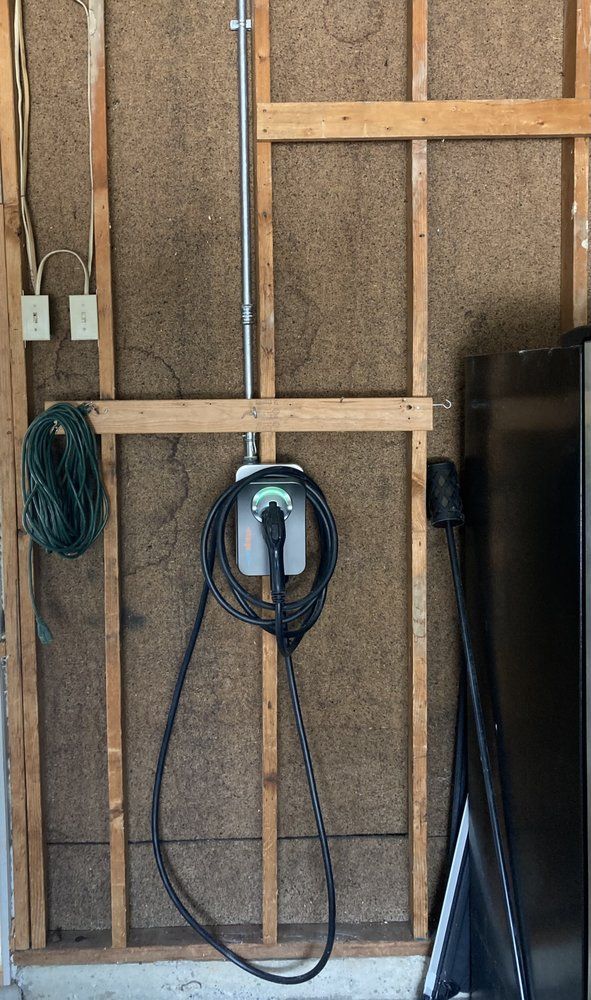 A power cord is hanging from a wooden wall in a garage.