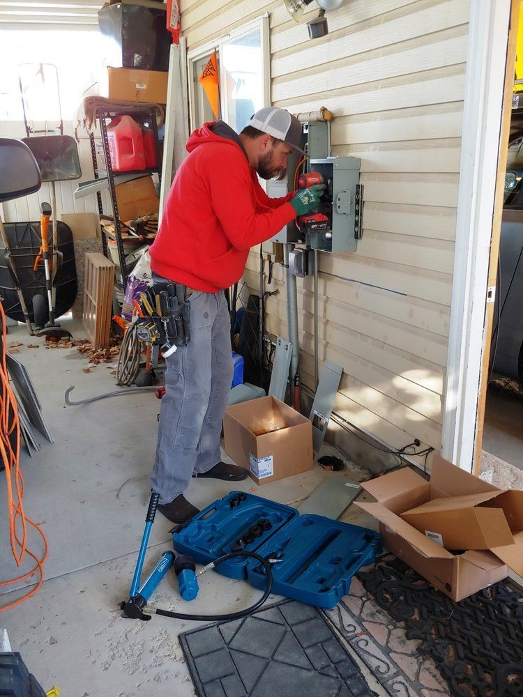 A man is working on an electrical box in a garage.