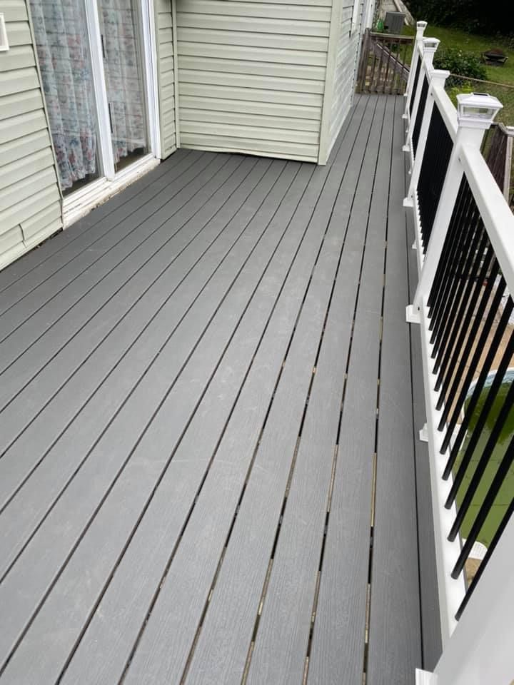 A high-angle view of a gray composite deck with white railings and black balusters next to a house with beige siding.