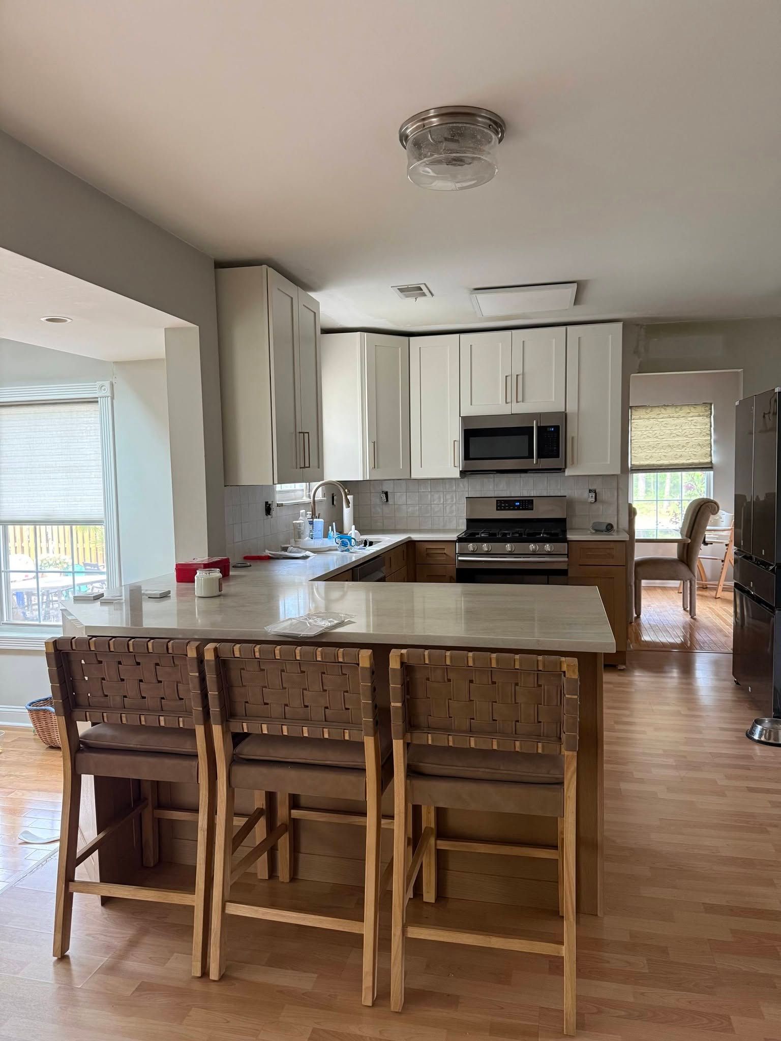Open kitchen with island, white cabinets, stainless appliances, and a dining table in the foreground.