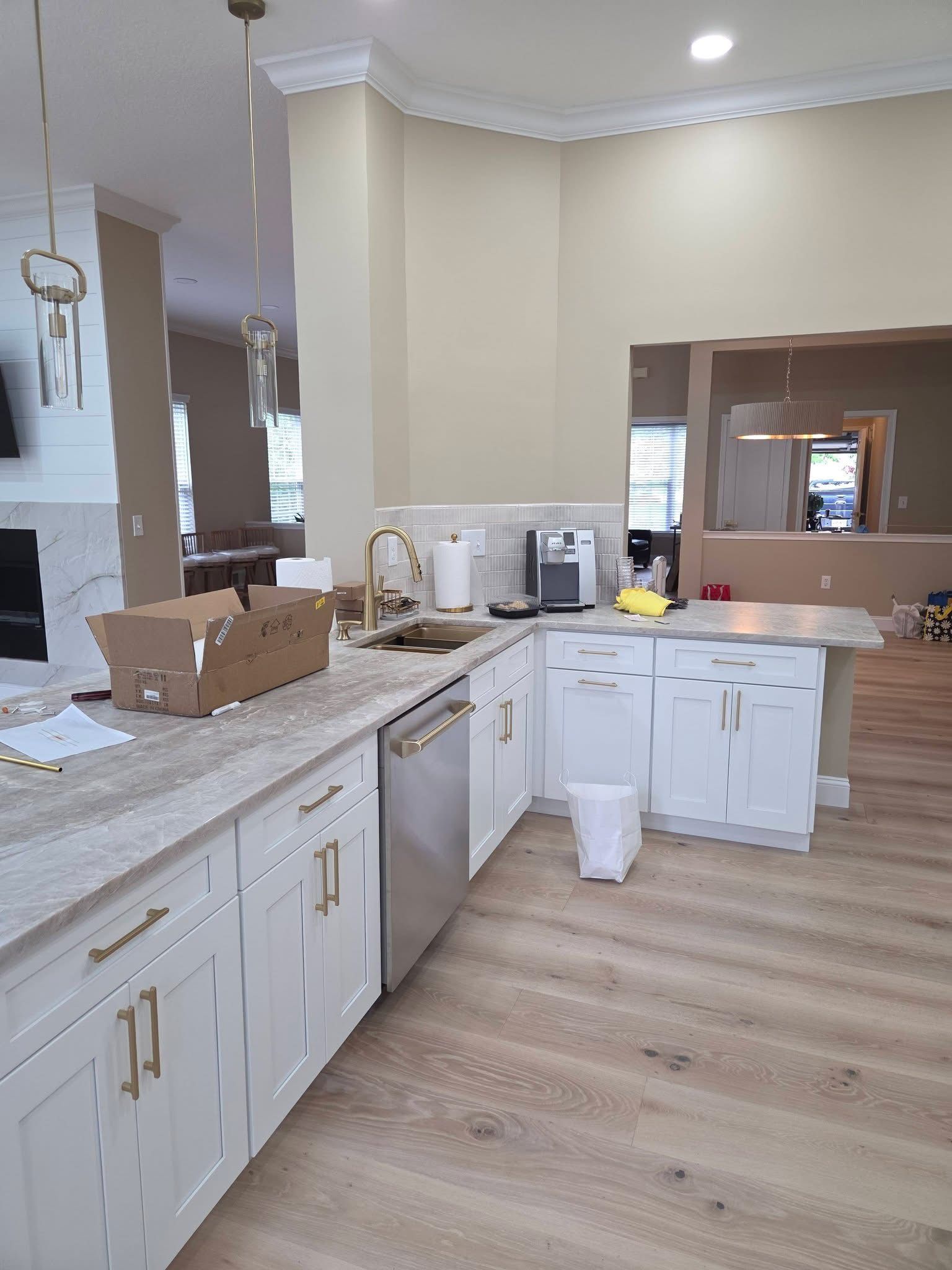 Bright kitchen with white cabinets, beige walls, and boxes on the countertop near the sink.
