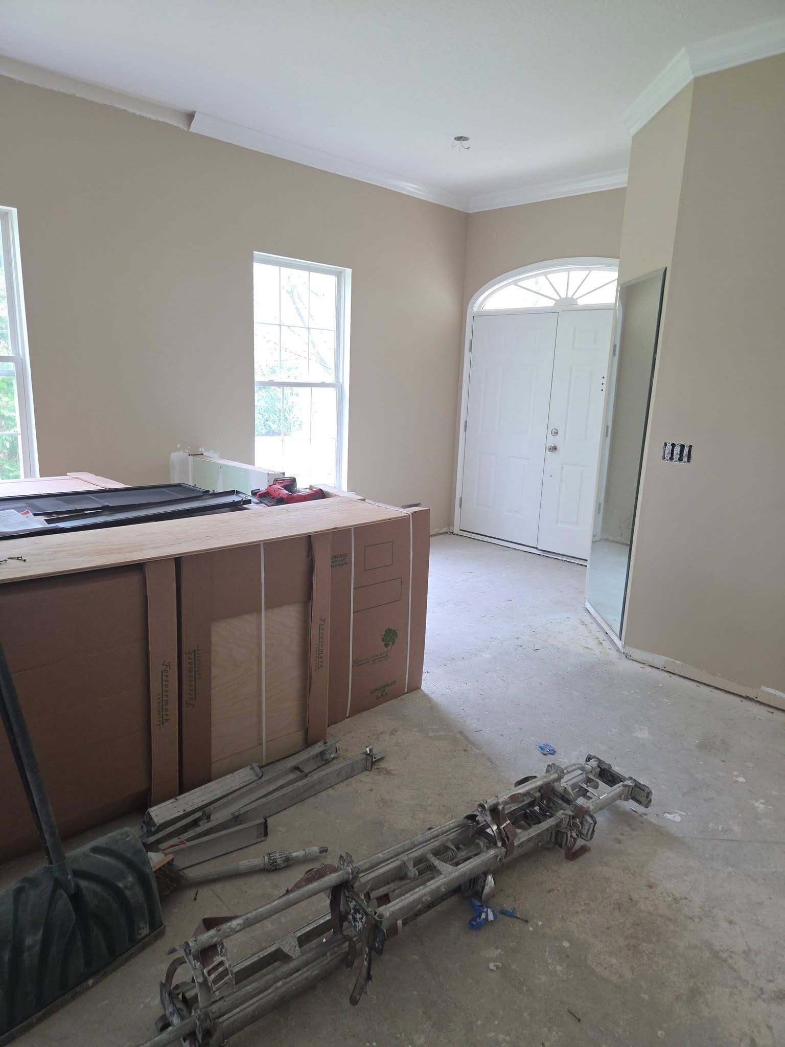 Renovation room with exposed framing, scattered tools, and white closet doors in a beige interior.