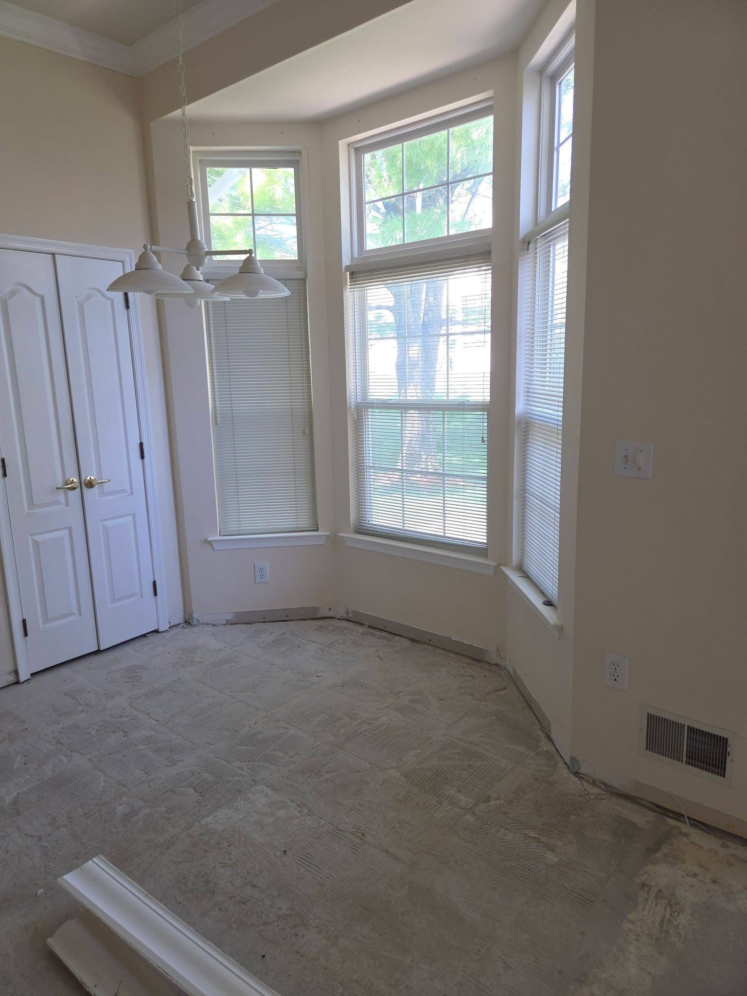 Empty carpeted room with bay windows, white shutters, and a closet door on the left