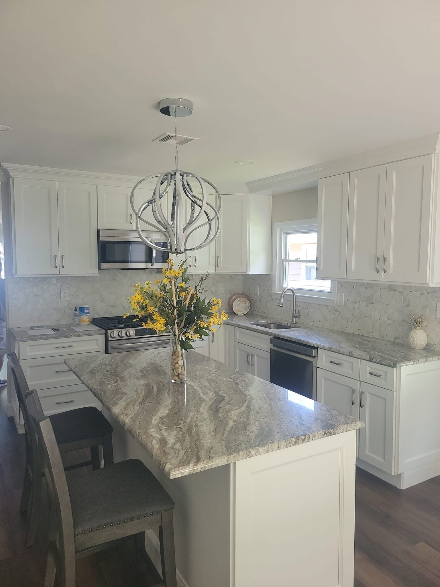 Bright white kitchen with marble island, pendant light, and yellow flower arrangement