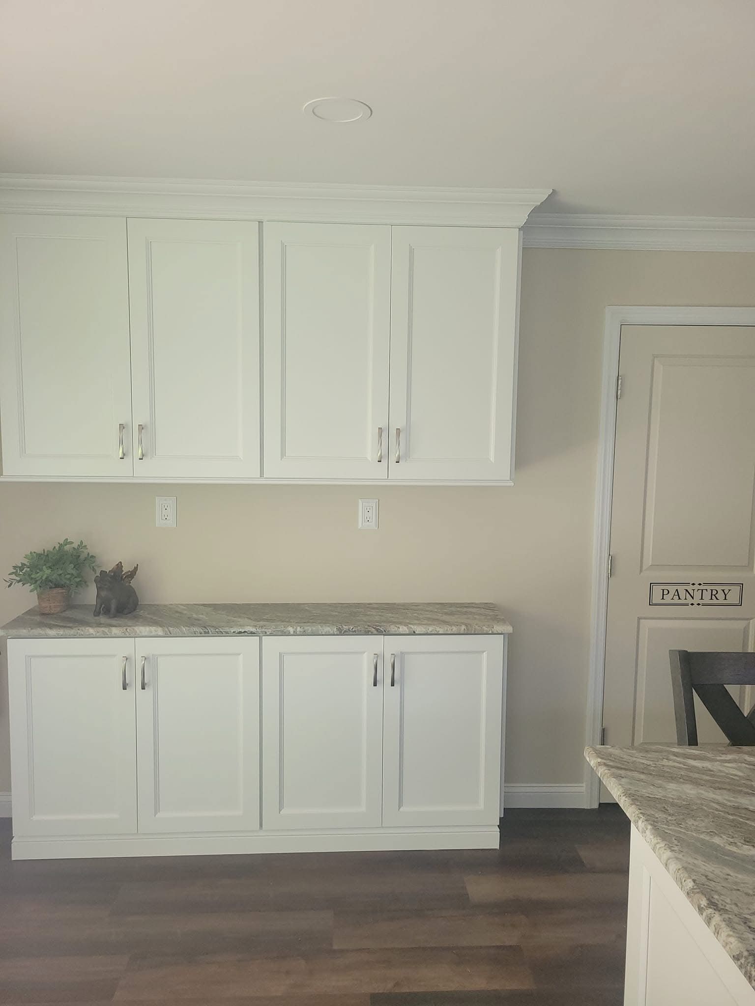 White kitchen cabinets and granite countertop in a bright room with hardwood floors.
