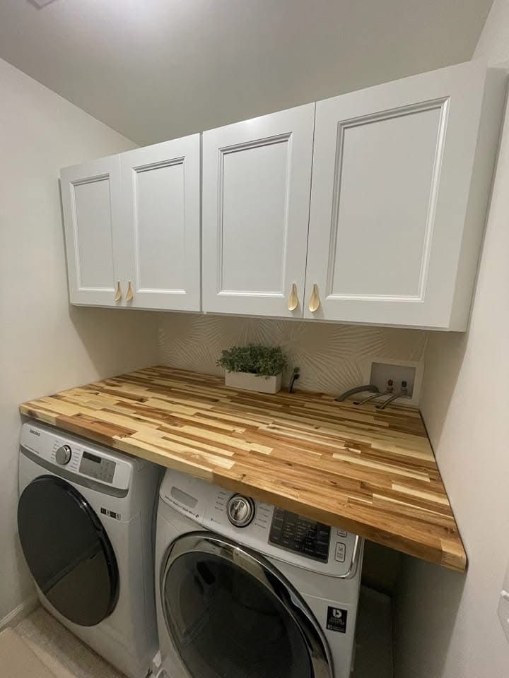 Laundry room with white cabinets, wooden countertop, and front-loading washer and dryer
