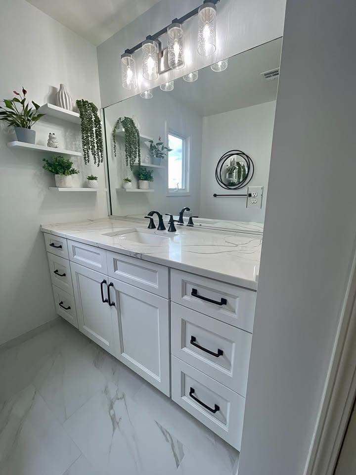 Bright white bathroom vanity with marble countertop, black fixtures, mirror, and pendant lights