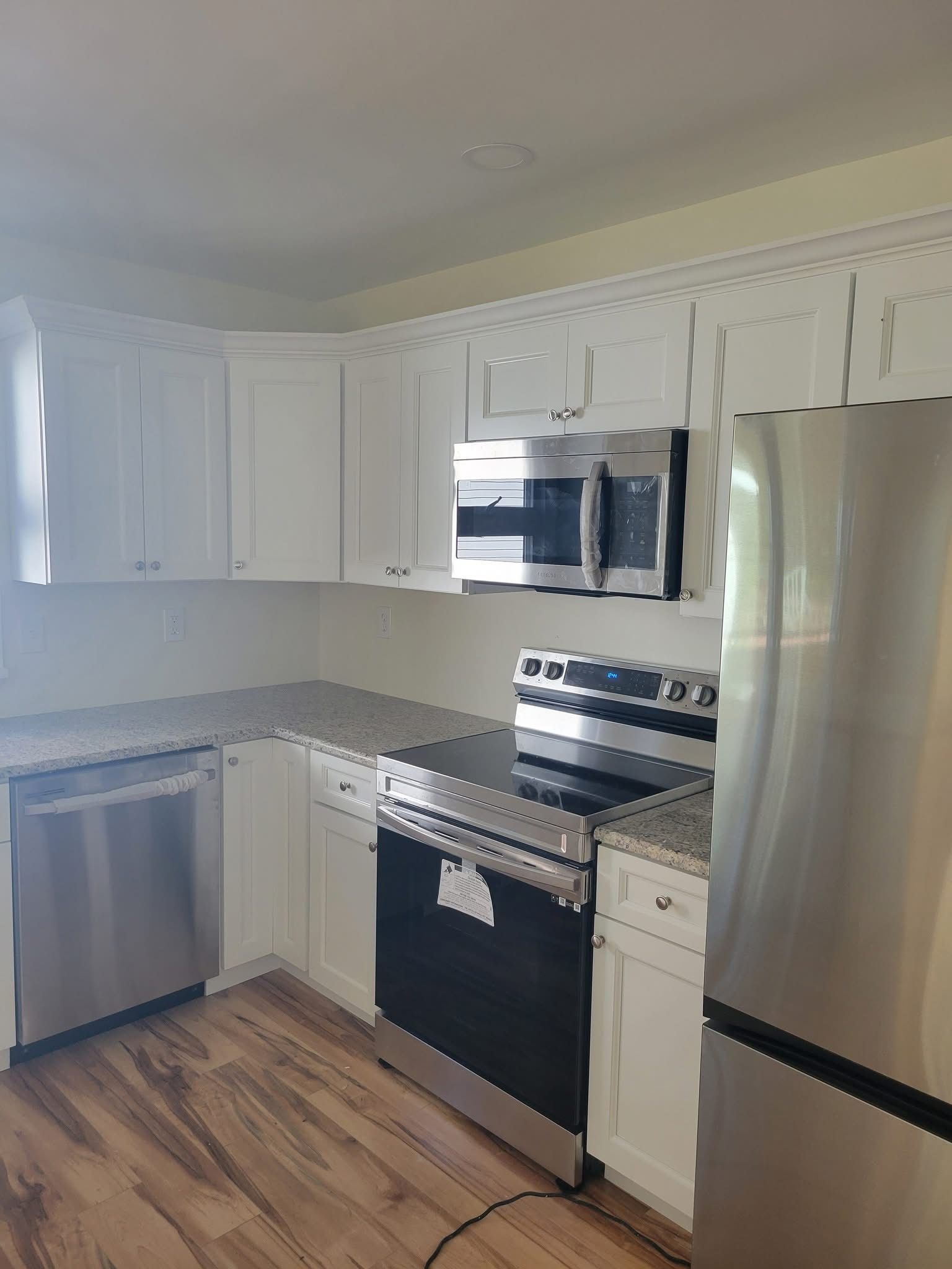 Modern kitchen with white cabinets, stainless steel appliances, and wood flooring