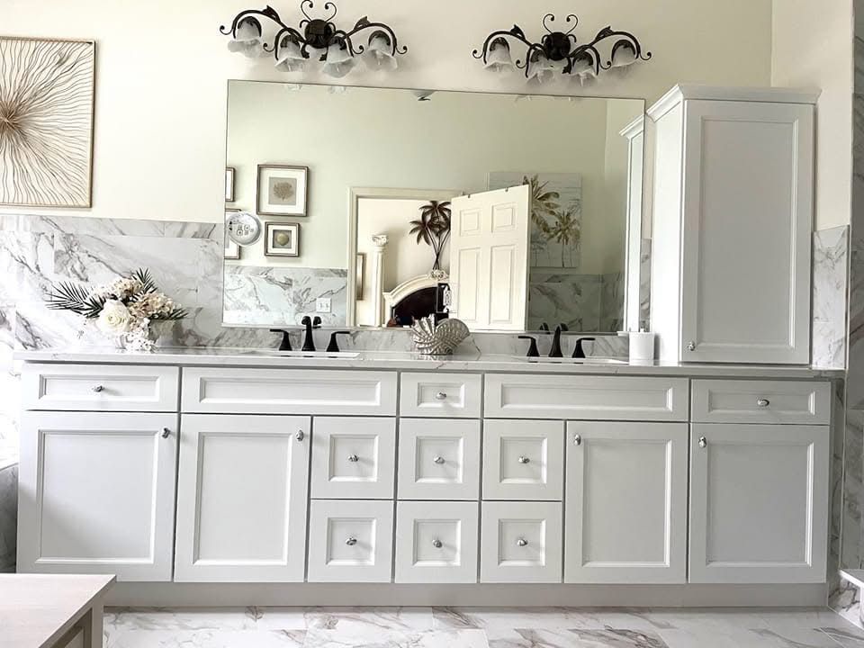 White bathroom vanity with mirror, cabinet, and wall sconces above a sink counter