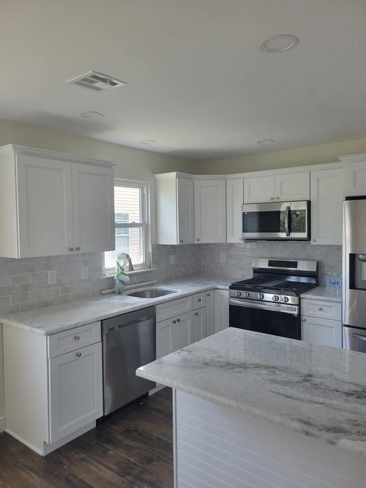 Bright white kitchen with marble island, stainless appliances, and light cabinets