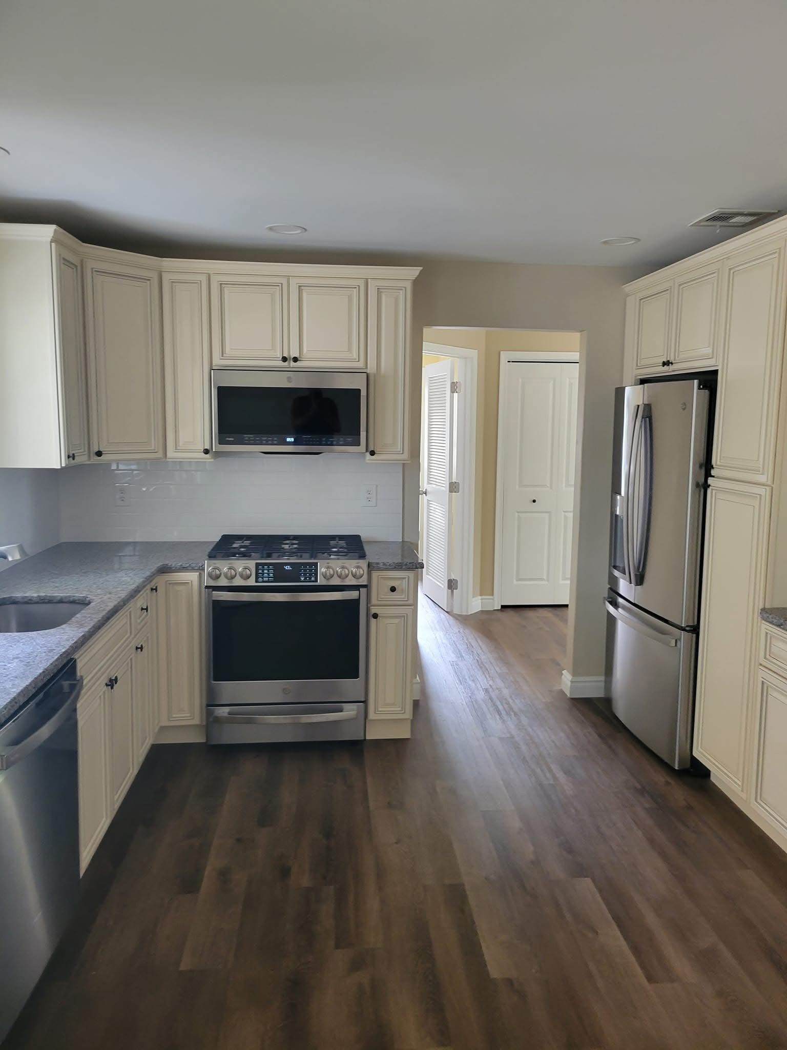 Bright kitchen with cream cabinets, stainless-steel appliances, and dark wood flooring