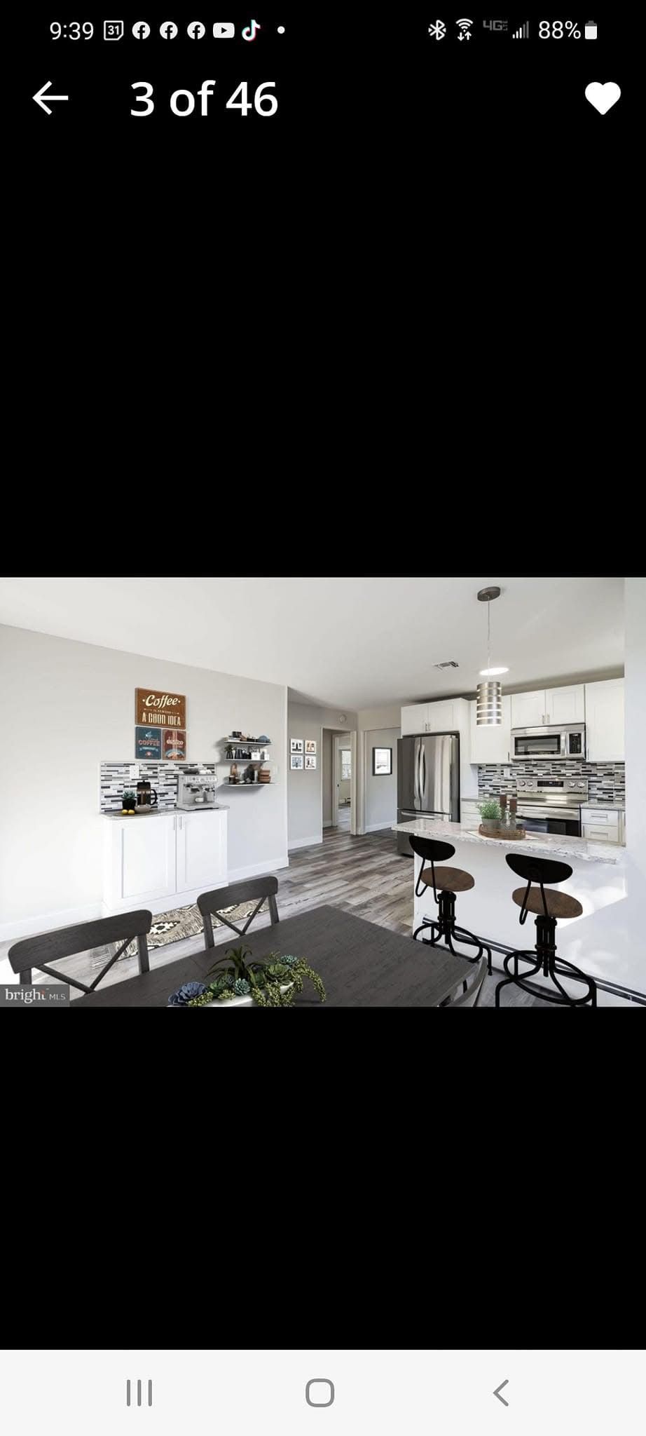 Bright modern room with white walls, mounted TV, desk, stools, and wall shelves on dark floors.