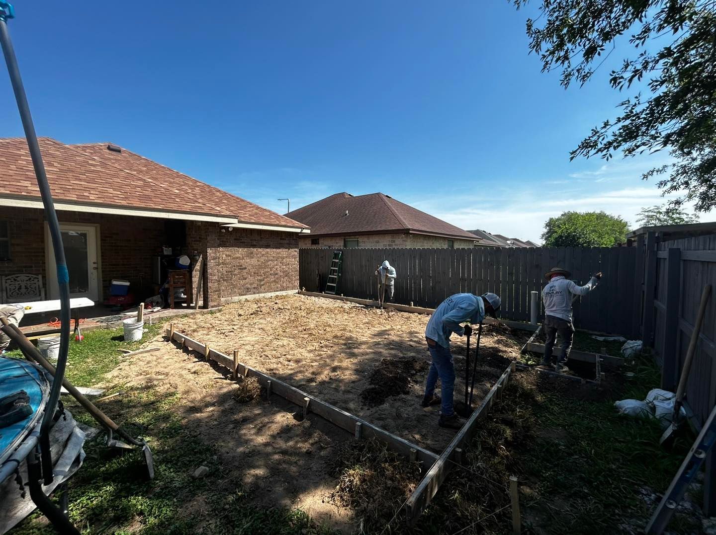 A group of men are working in a backyard in front of a house.