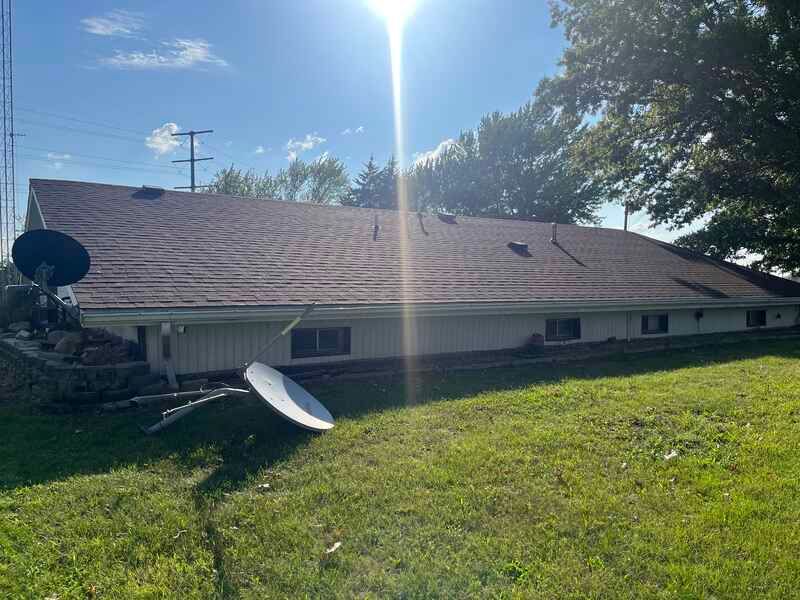 Low house with a sloped roof and satellite dish on a sunny grassy yard