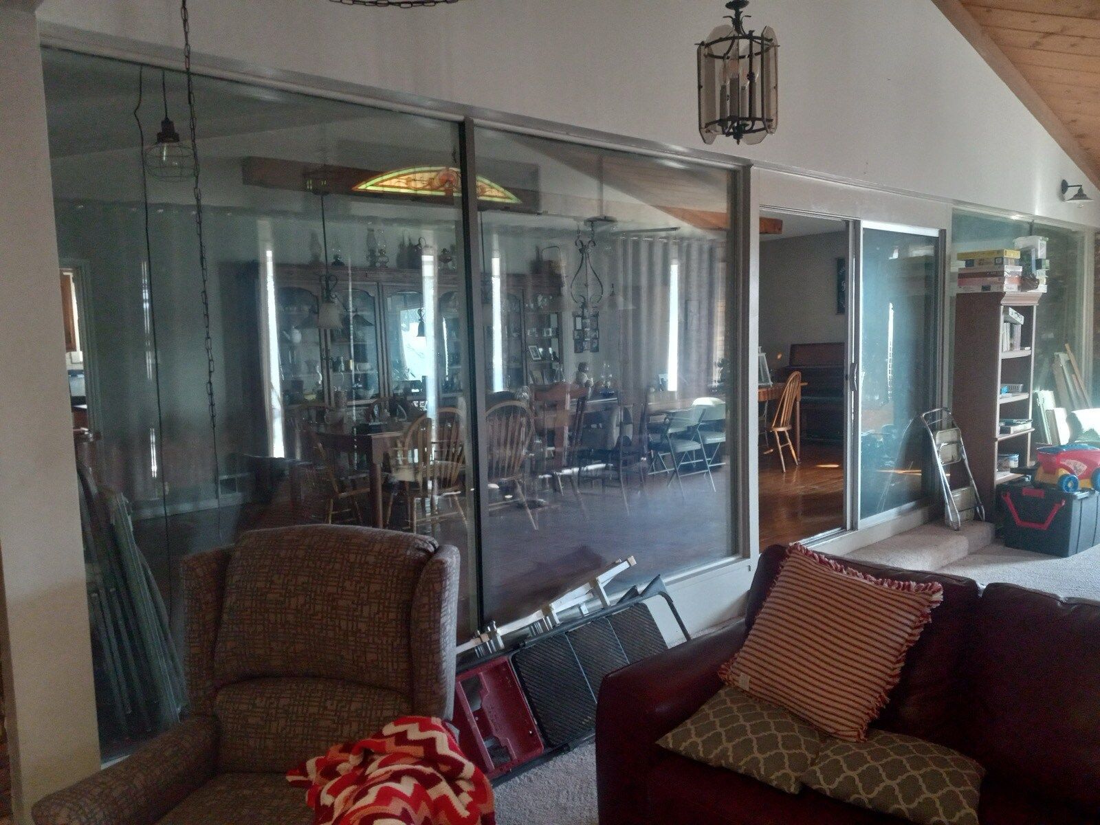 Modern living room with glass wall, armchairs, and a red sofa in warm indoor light